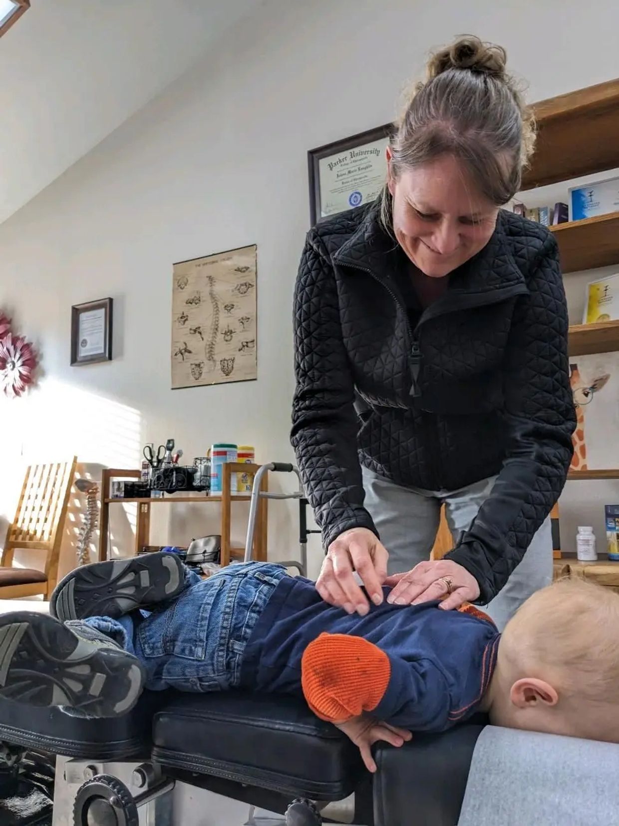 Small boy lying face down on a chiropractic table while Dr. Jo evaluates his spine.