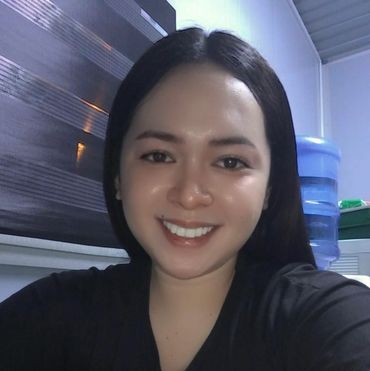 A smiling woman with long black hair in a dark room.