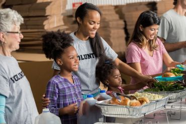 Volunteers serving food to children at a community event.