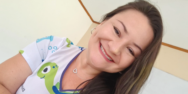 Smiling woman in a colorful shirt with sea creature designs, sitting indoors.