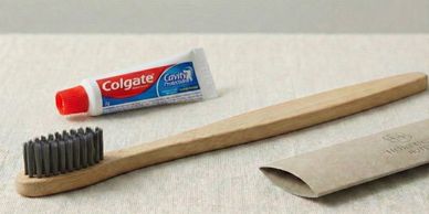 Eco-friendly bamboo toothbrush with Colgate toothpaste tube and paper packaging.