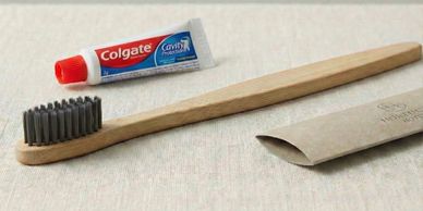 Eco-friendly bamboo toothbrush with Colgate toothpaste tube and paper packaging.