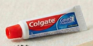 Eco-friendly bamboo toothbrush with Colgate toothpaste tube and paper packaging.