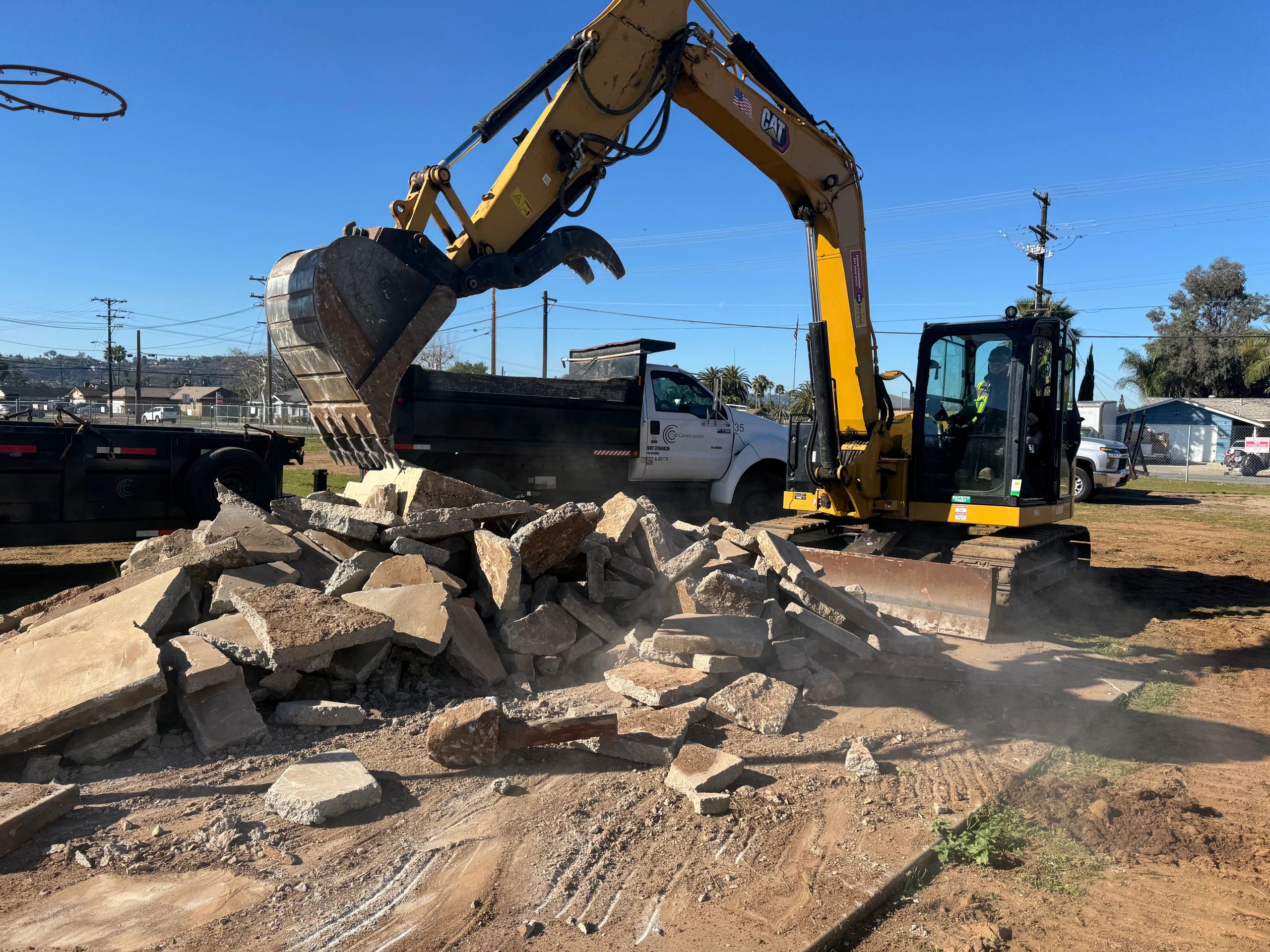Excavator loading rubble into a dump truck on a sunny day.