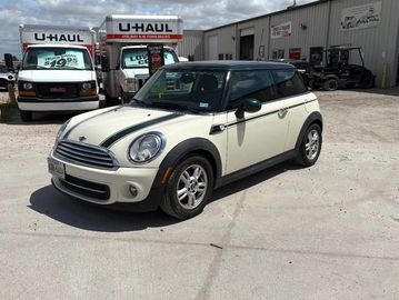 White Mini Cooper with black racing stripes parked in a lot.