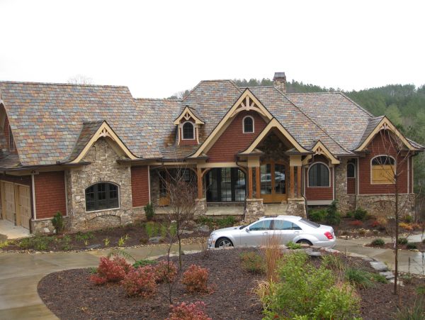 Large stone and wood house with a parked silver car.