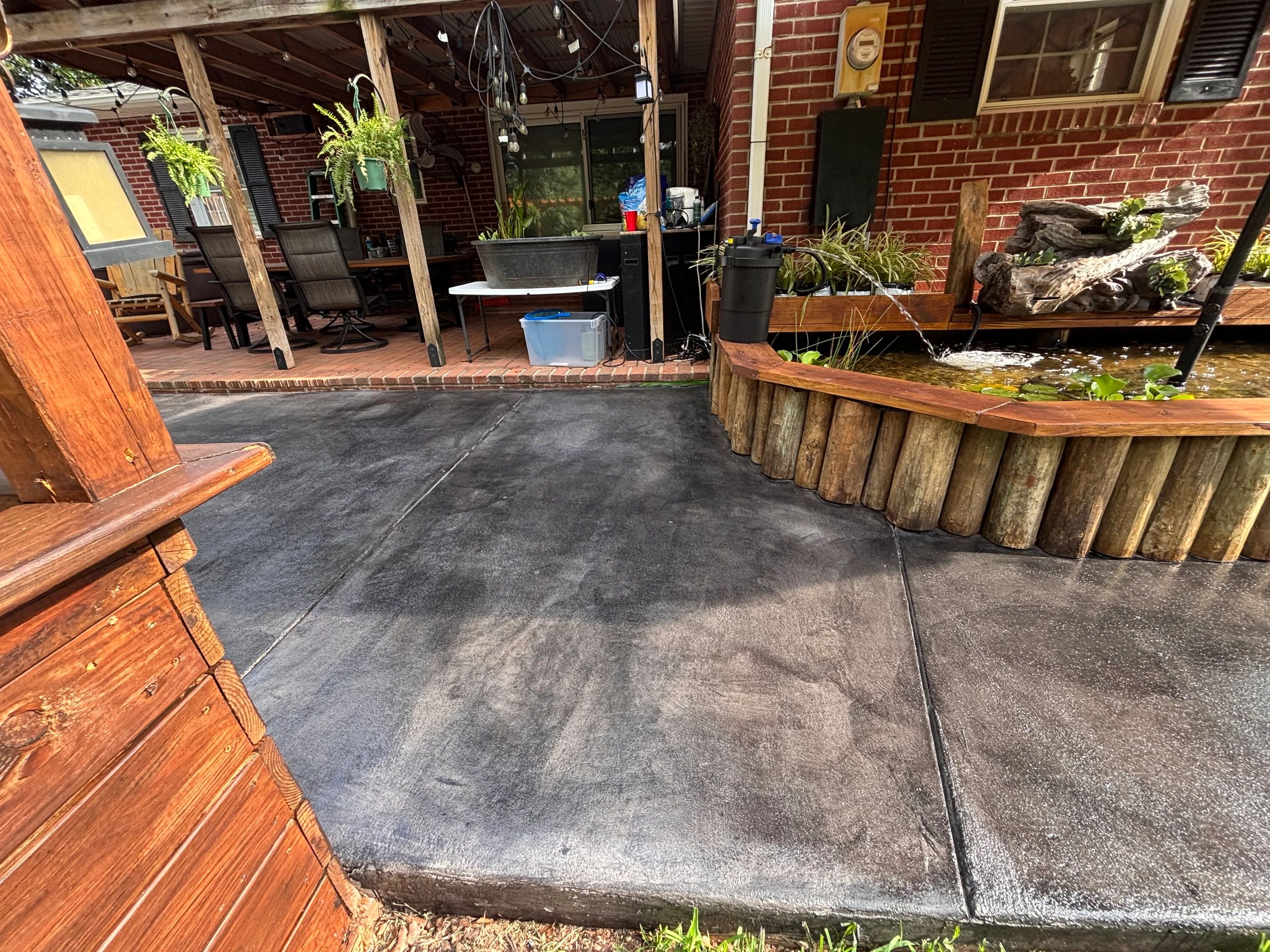 Backyard patio with wooden pond and covered seating area.