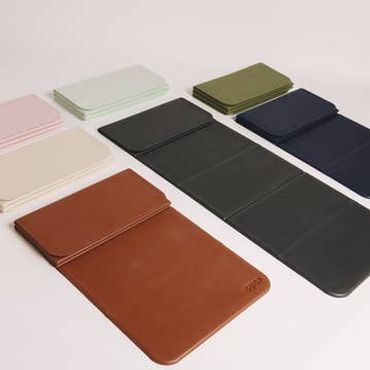 Assorted leather and fabric pouches in various colors arranged on a white surface.