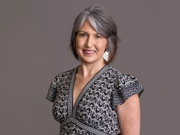 Smiling silver-haired woman in patterned dress.