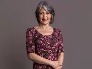 Smiling older woman in a patterned dress.