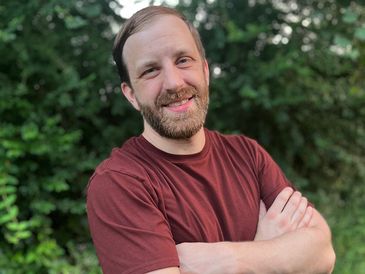 Smiling man with beard posing outdoors.