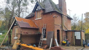 Old brick house undergoing roof repairs with tools and materials around.