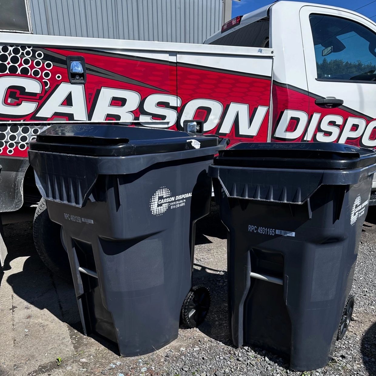 Two black Carson Disposal trash bins outdoors.