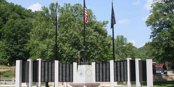 Picture of memorial with white pillars and flags with names of soldiers written on black granite.