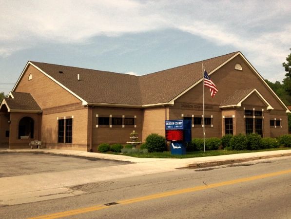 Picture of the Jackson County Public Library. A brown brick building with American flag.