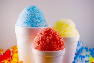 Three colorful shaved ice treats in white cups with a festive background.