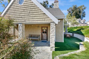 A cozy porch with stone pillars and wooden bench.