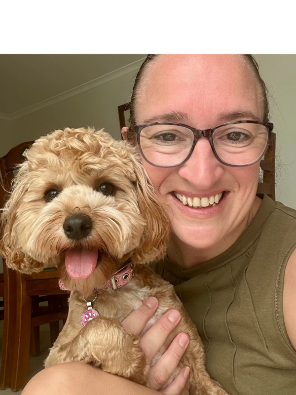 Smiling woman with glasses holding a happy, curly-haired dog.