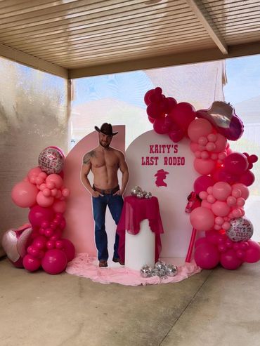 Pink rodeo-themed party setup with balloons and cowboy cutout.