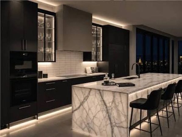 Modern kitchen with marble island and city view at night.
