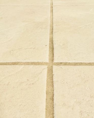 Close-up of beige tiles with dirty grout lines.
