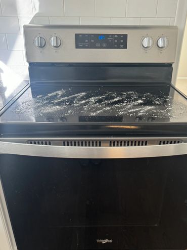 Modern Whirlpool electric stove with spilled powder on glass cooktop.