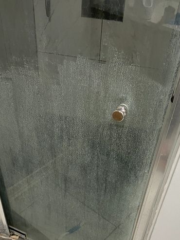 Dirty shower door with a tile cleaner brush. MID CLEAN