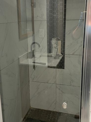 Modern shower with glass door and hexagonal floor tiles. COMPLETE CLEAN