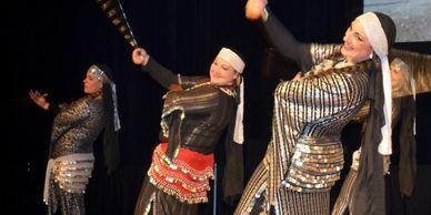 Three dancers in black and silver swinging sticks.