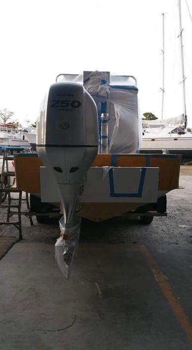 Rear view of a boat with a Honda 250 VTEC outboard motor indoors.