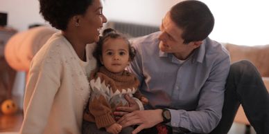 A family with a child sitting together in a cozy living room.