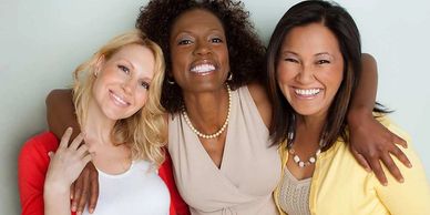 Three women smiling and embracing each other warmly.