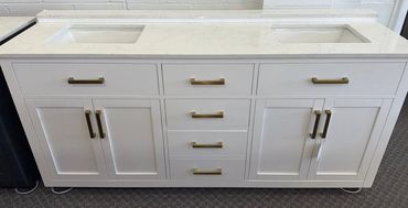 White double vanity cabinet with marble countertop and brass handles.