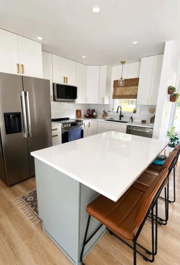 Modern kitchen with white cabinetry and brown leather chairs.
