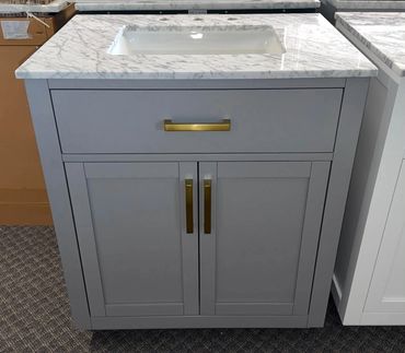 Gray bathroom vanity with marble countertop and brass handles.