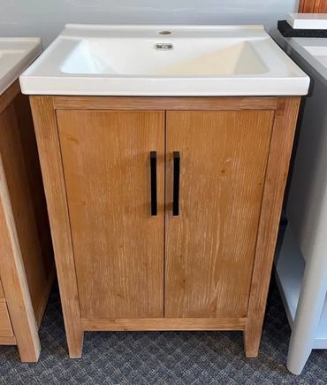 Wooden bathroom vanity with white sink and black handles.