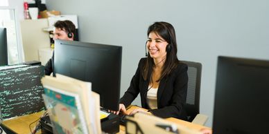 Smiling female customer service representative wearing a headset at her desk.