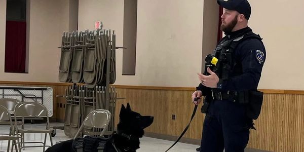 Police officer training with a K9 dog indoors.