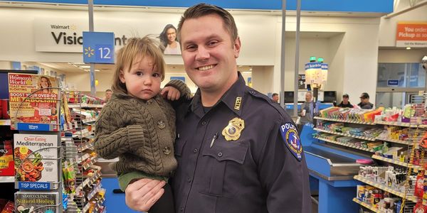 Photo of Det. Tim Bakula and child at Caring for Kids/Shop with a Cop community event