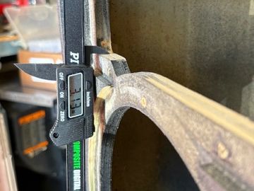 Digital caliper measuring a circular metal object's thickness.
