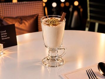 Elegant creamy drink garnished with cinnamon sticks.