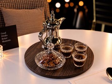 Elegant coffee setup with a silver pot and cups on a wooden tray.