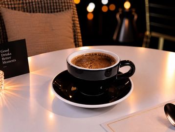 Cup of coffee on a table with warm lighting.