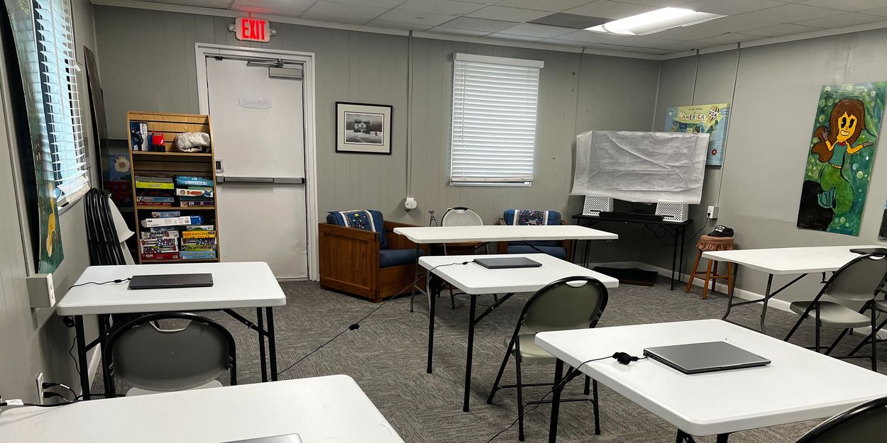 Classroom with laptops on tables and a cozy seating area.