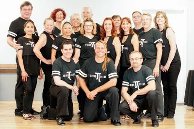 Group photo of people in matching black shirts posing indoors.