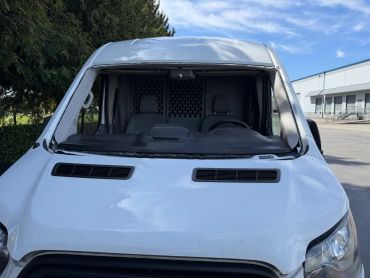 Van preparing to install windshield on a clear day.