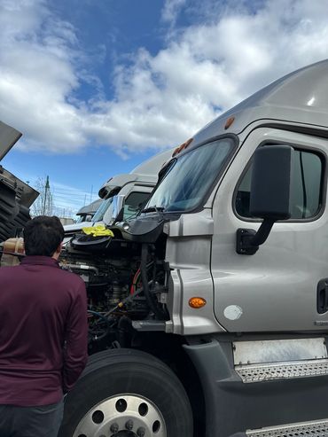 Man inspecting the engine of a semi-truck.