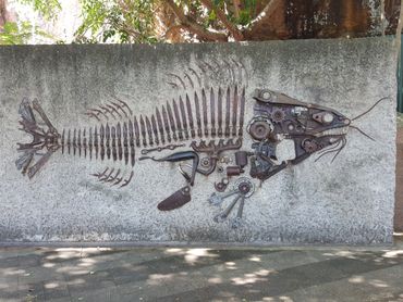 Fish skeleton art made from rusty metal parts on a wall.