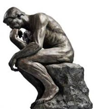 Bronze statue of a man deep in thought, seated on a rock.