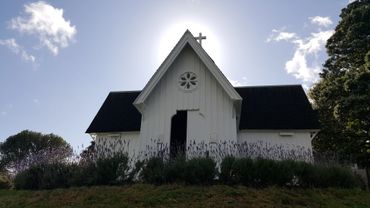 Small white church with a cross and lavender plants in front.